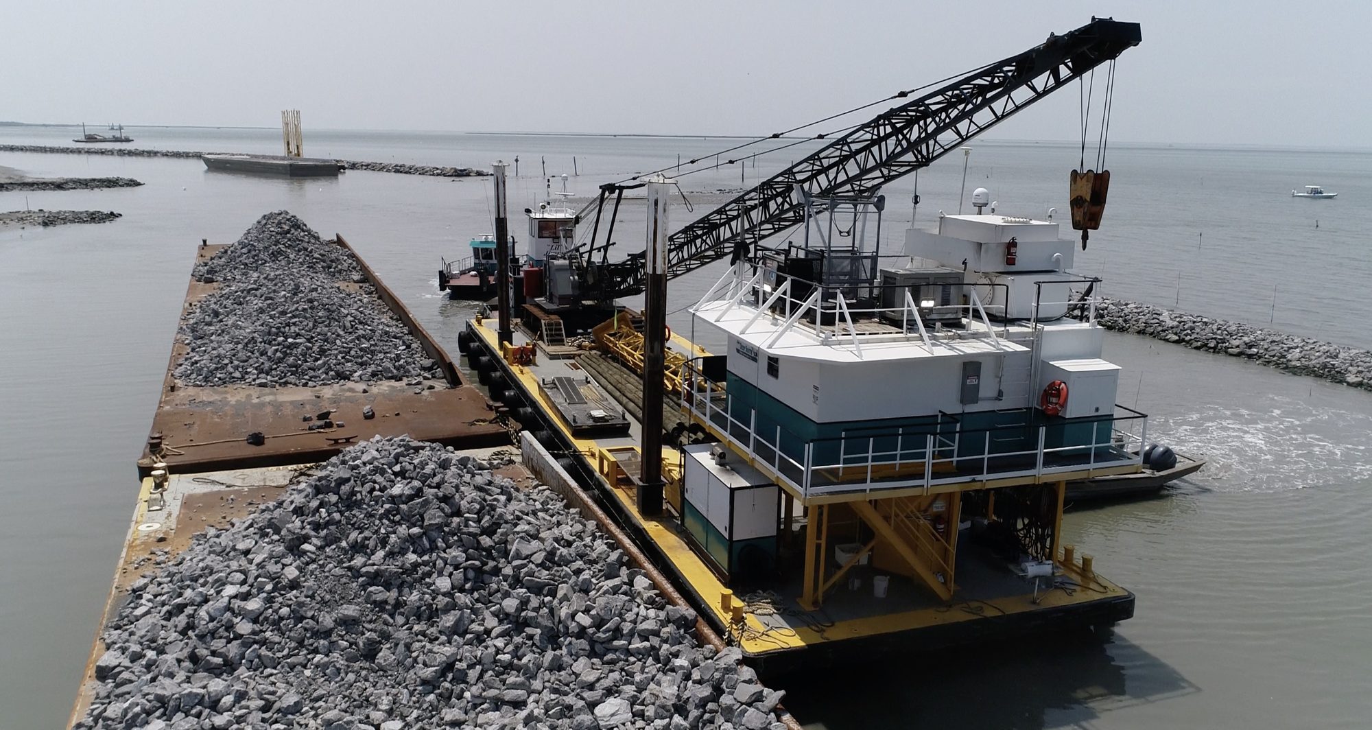 Bunk barge and crane alongside a barge loaded with rock