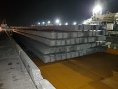 Concrete pilings staged on a barge at night