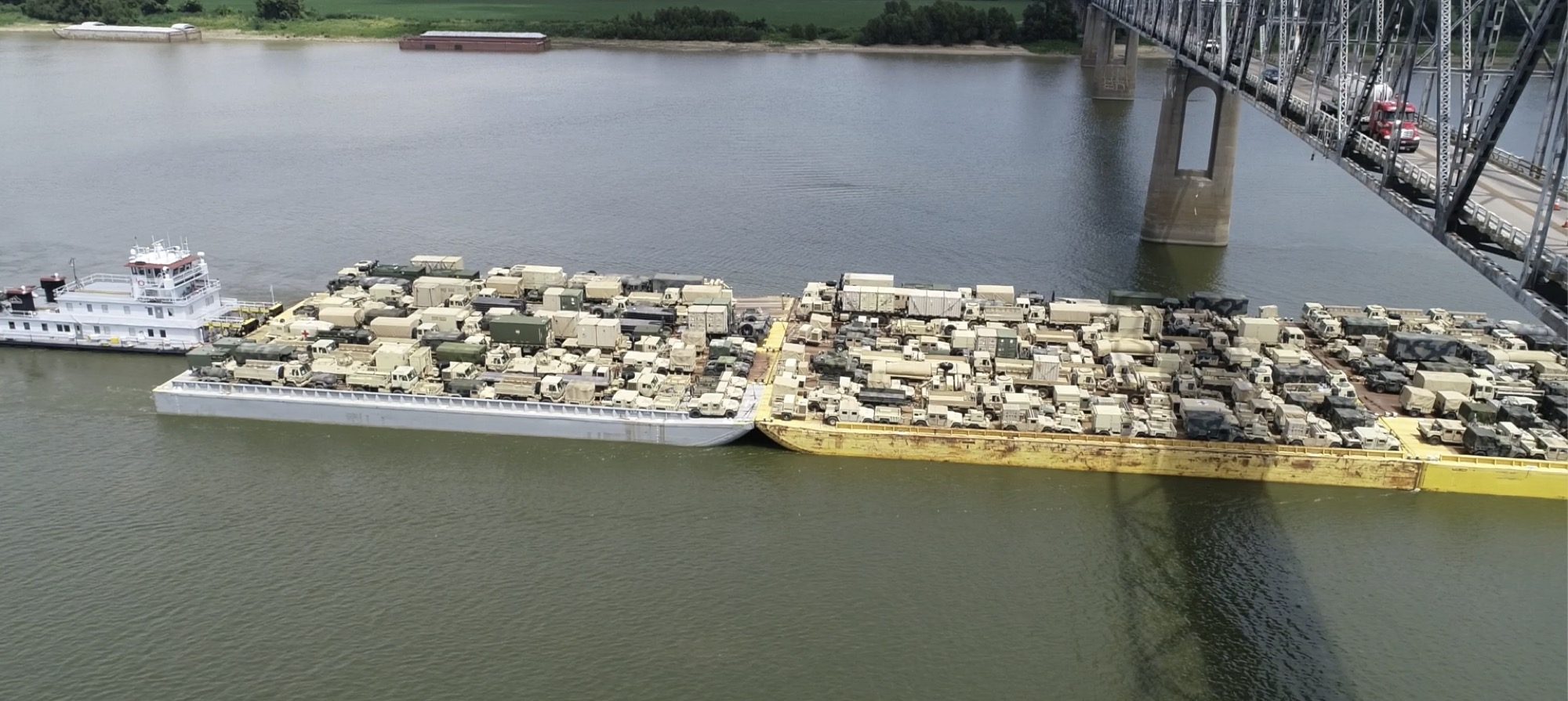 Military move barges passing under a Mississippi River bridge