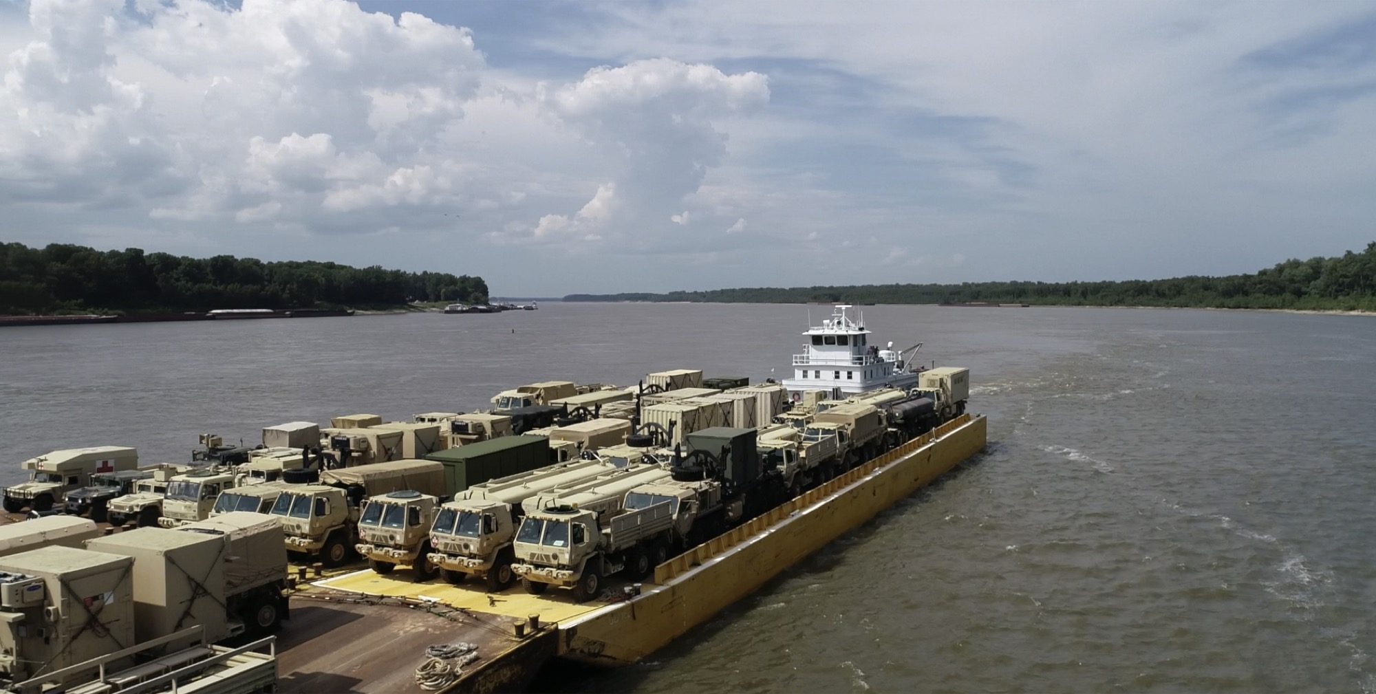 Loaded military equipment barges heading downriver