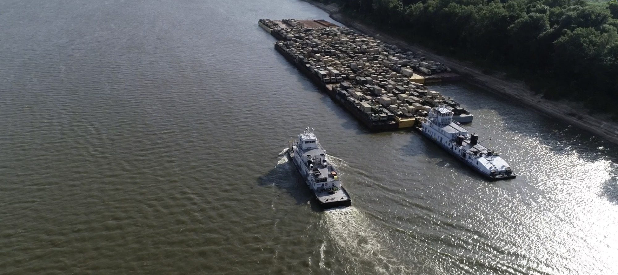 Towboats pushing loaded military equipment barges
