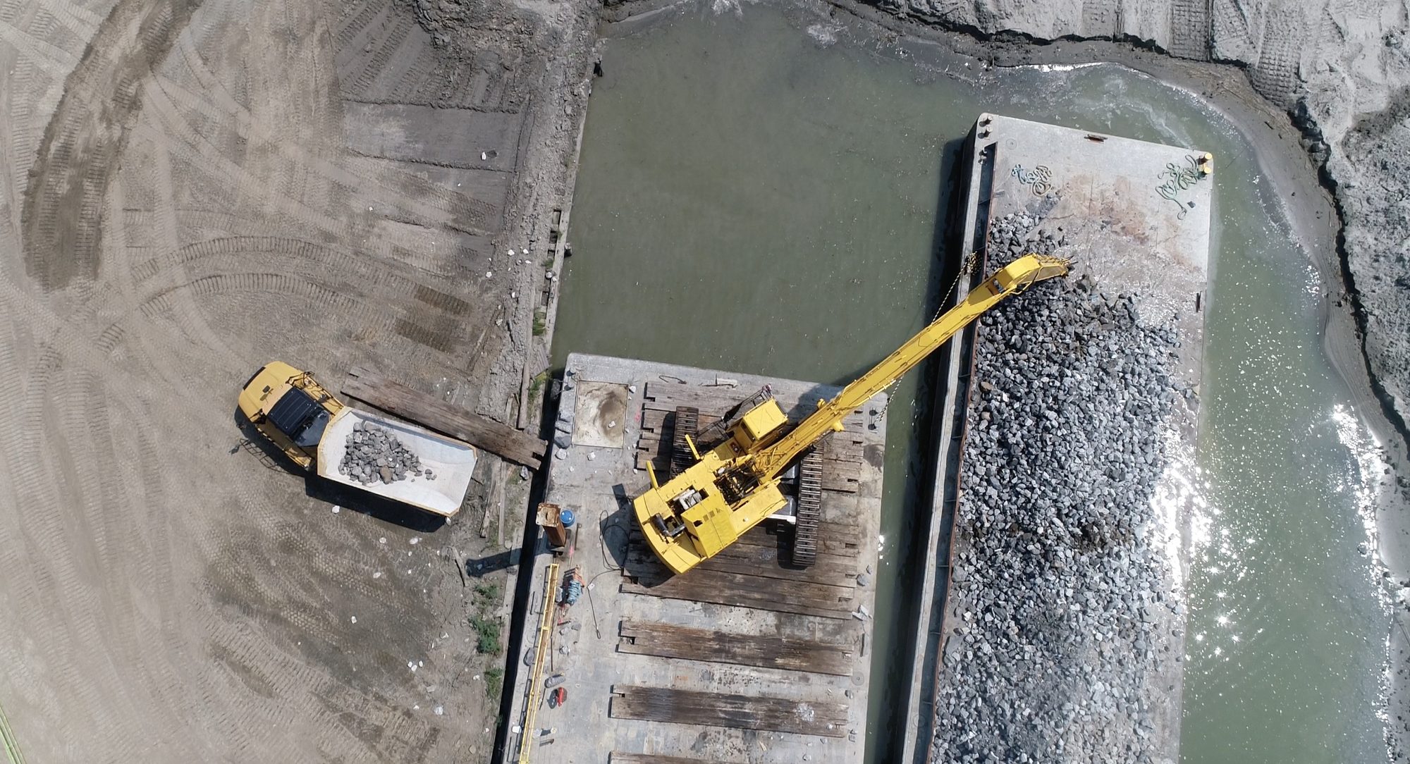 Overhead view of an excavator loading a barge