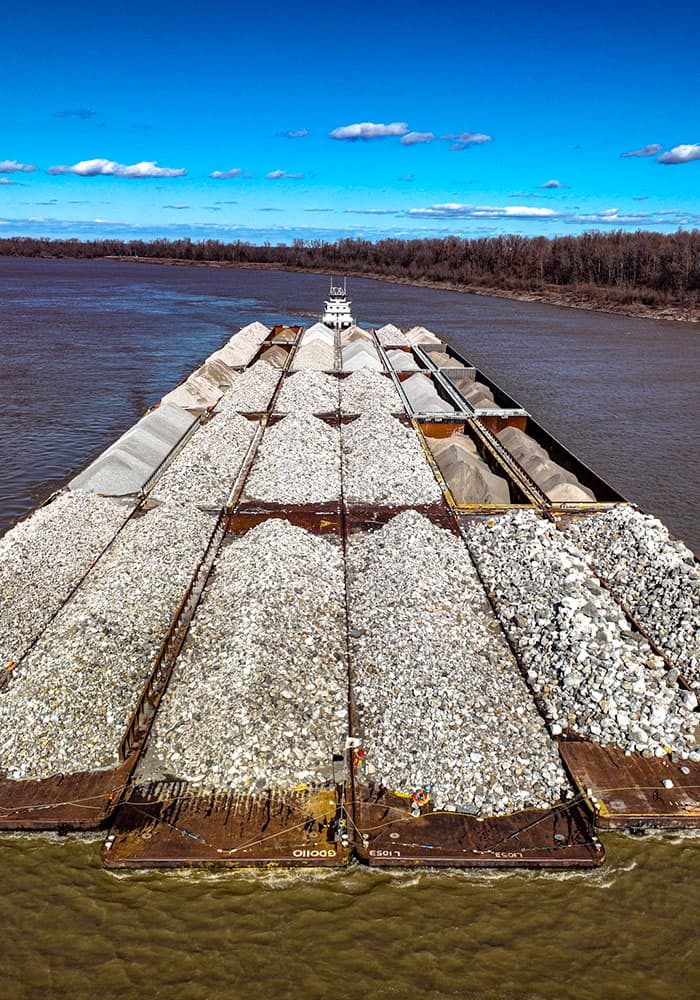 Towboat pushing loaded rock barges on the river